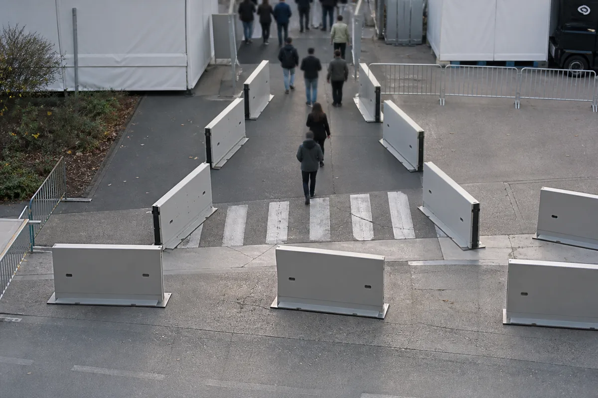 Vue en plan d&rsquo;un accès de manifestation filtré par une chicane de barrières mobiles avec passage piéton