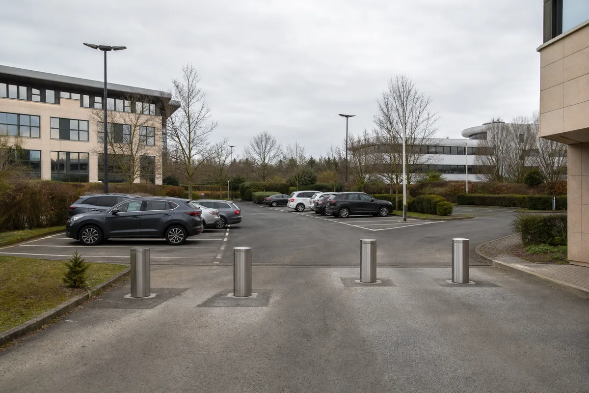 Plusieurs bornes escamotables alignées à l&rsquo;entrée d&rsquo;un parking d&rsquo;entreprise