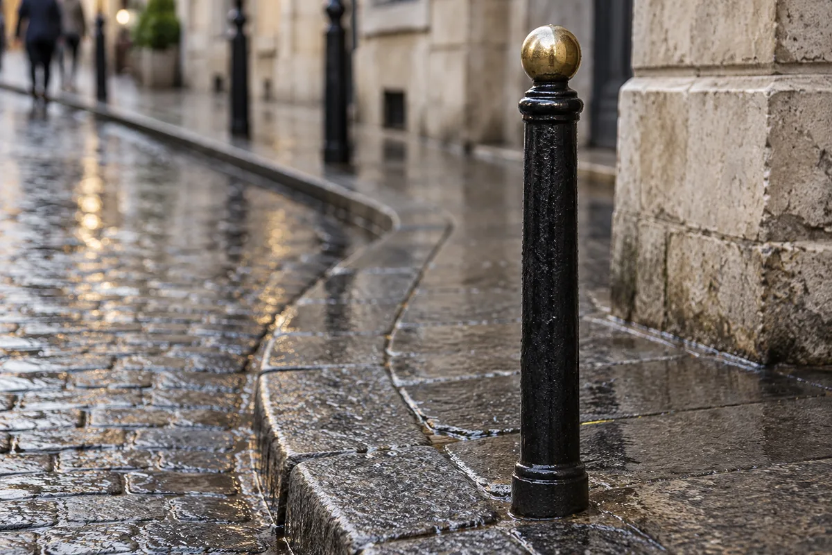 Potelet en fonte noire à tête dorée à l&rsquo;angle d&rsquo;un trottoir pavé de centre ancien